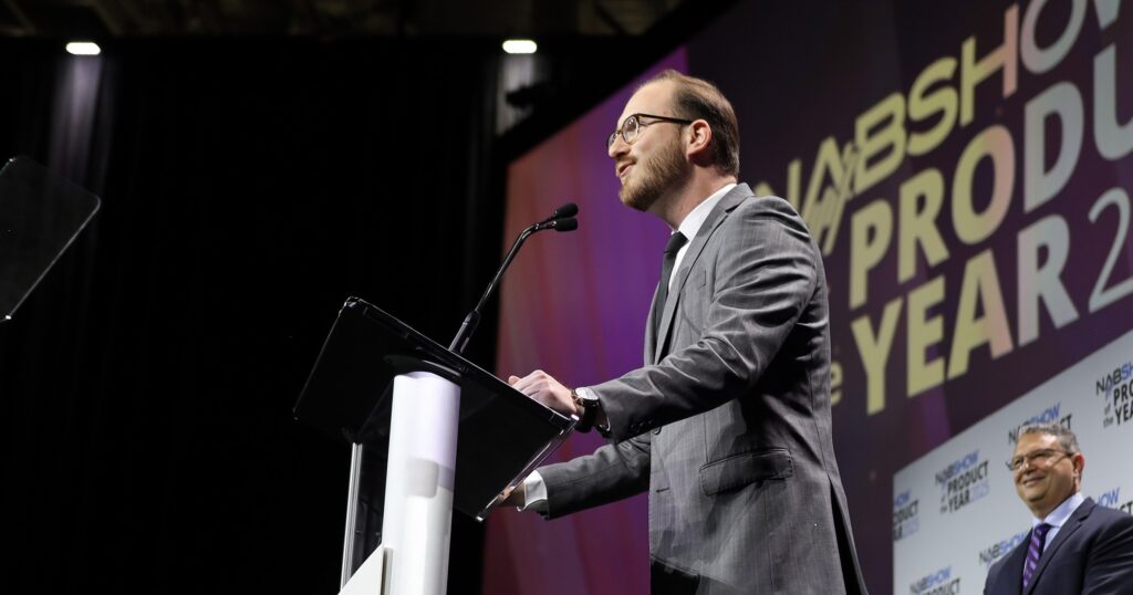 A man stands at the podium during the 2025 NAB Show Product of the Year Awards Ceremony.